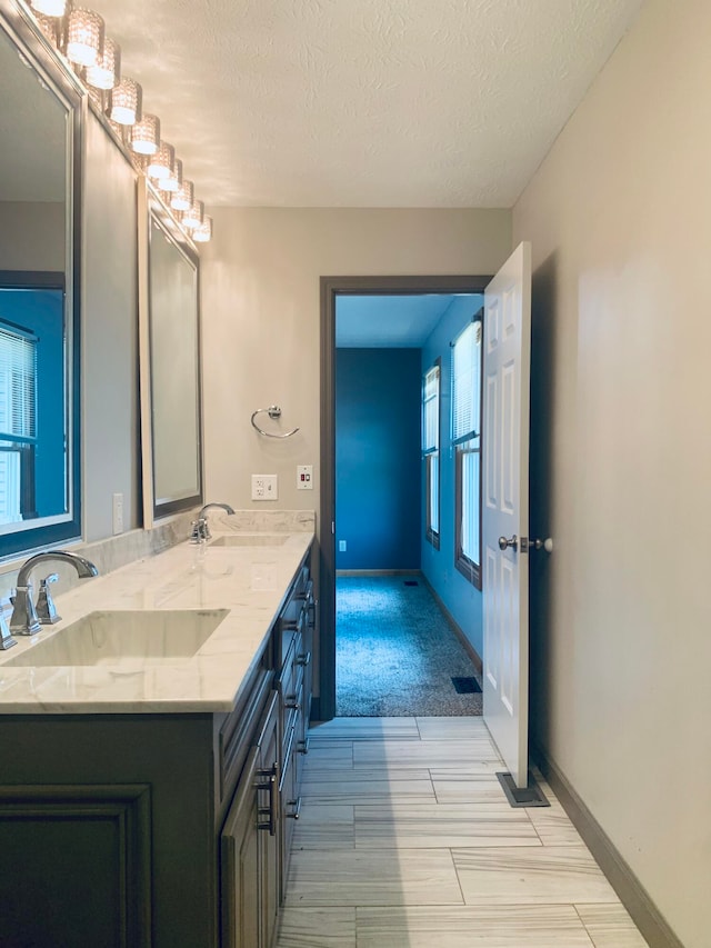 bathroom with a textured ceiling, vanity, and wood-type flooring