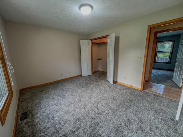 unfurnished bedroom featuring a textured ceiling, a closet, and hardwood / wood-style flooring