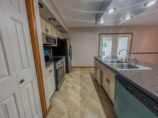 kitchen with dark stone countertops, stainless steel appliances, white cabinetry, and sink