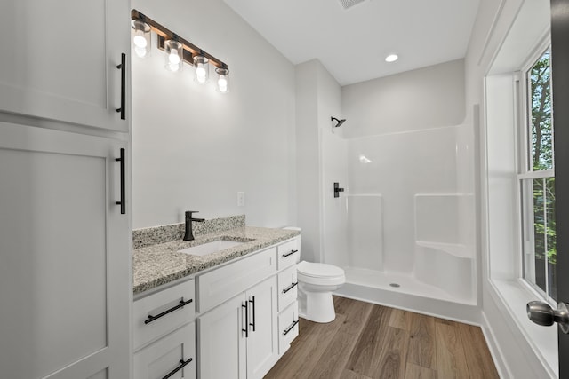 bathroom with a shower, wood-type flooring, toilet, and a healthy amount of sunlight