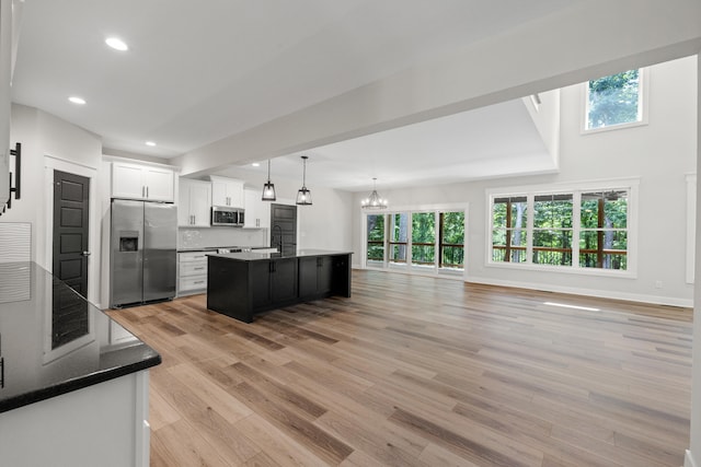 kitchen with pendant lighting, a center island, decorative backsplash, appliances with stainless steel finishes, and white cabinetry