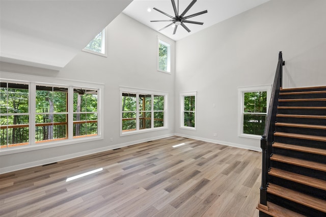 unfurnished living room with light hardwood / wood-style flooring, high vaulted ceiling, and ceiling fan