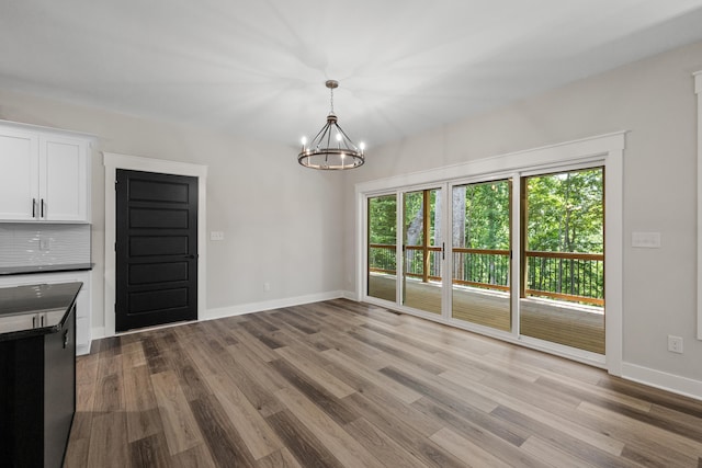 unfurnished dining area with light hardwood / wood-style floors and an inviting chandelier