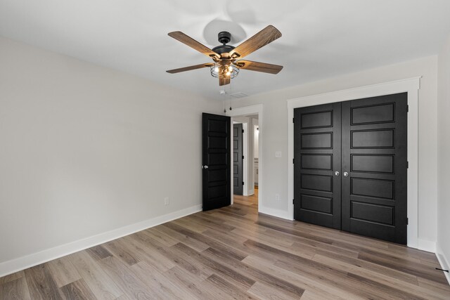 unfurnished bedroom with ceiling fan, a closet, and hardwood / wood-style flooring