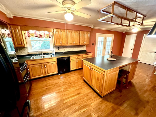 kitchen featuring dishwasher, a kitchen island, decorative backsplash, sink, and ceiling fan