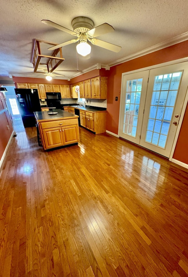 kitchen with black appliances, light wood-type flooring, crown molding, and a textured ceiling