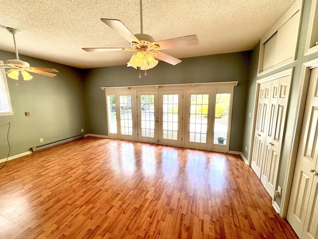 spare room featuring a textured ceiling, baseboard heating, light hardwood / wood-style floors, and ceiling fan