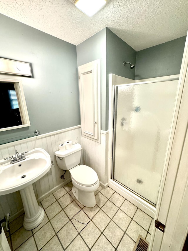 bathroom with an enclosed shower, tile patterned flooring, toilet, and a textured ceiling