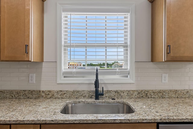 interior details with a sink, decorative backsplash, and light stone countertops