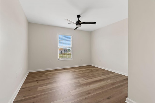 spare room with baseboards, ceiling fan, visible vents, and wood finished floors