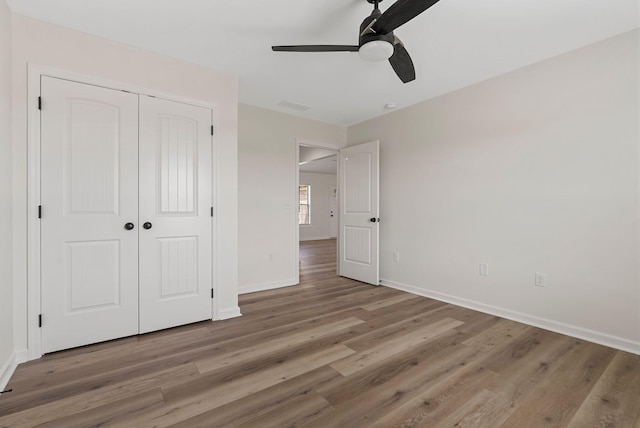 unfurnished bedroom with ceiling fan, a closet, wood finished floors, and baseboards