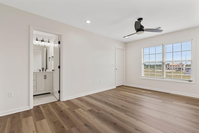 unfurnished bedroom featuring baseboards, wood finished floors, and ensuite bathroom