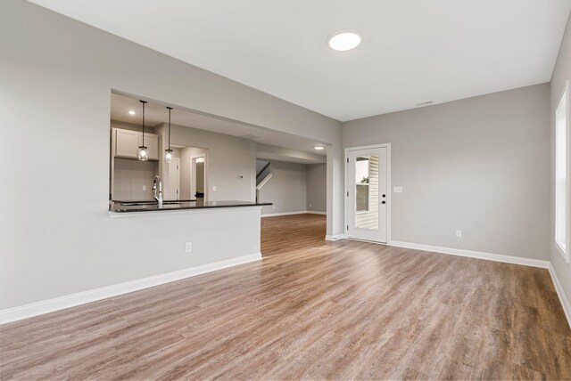 unfurnished living room featuring light wood-type flooring and sink