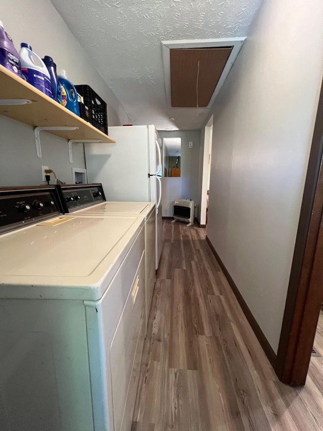 clothes washing area with washer and clothes dryer, a textured ceiling, and hardwood / wood-style flooring