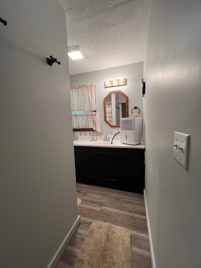 bathroom with wood-type flooring, vanity, and a textured ceiling