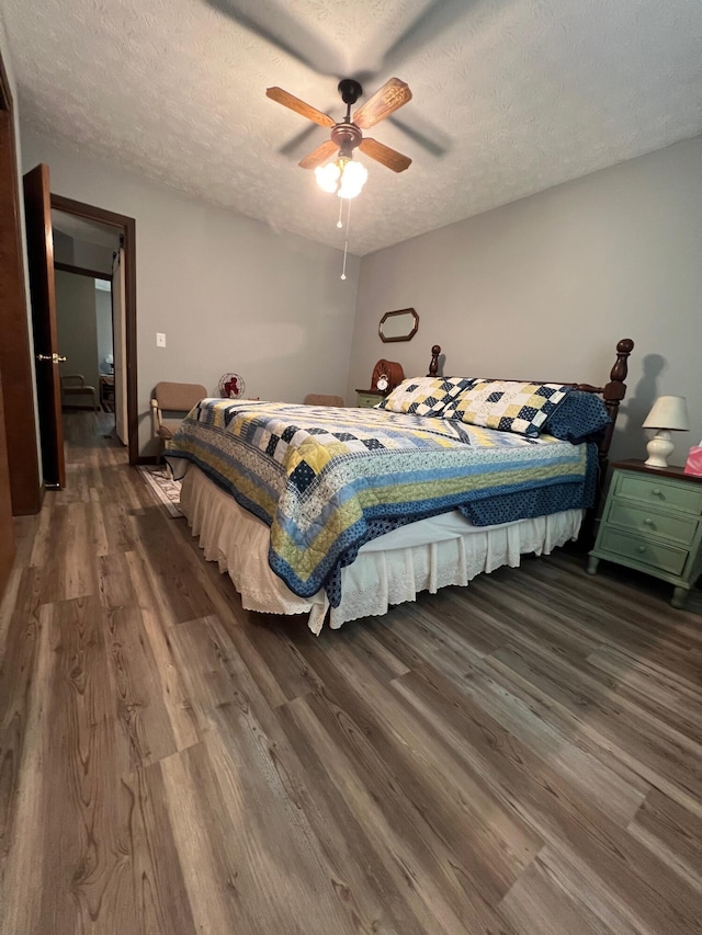 bedroom with dark hardwood / wood-style floors, ceiling fan, and a textured ceiling