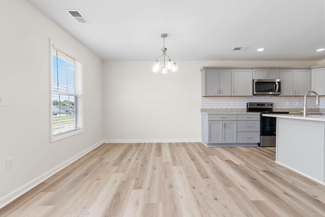 kitchen with tasteful backsplash, light wood-type flooring, range with electric cooktop, and gray cabinetry