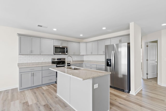 kitchen featuring tasteful backsplash, sink, stainless steel appliances, and light hardwood / wood-style flooring