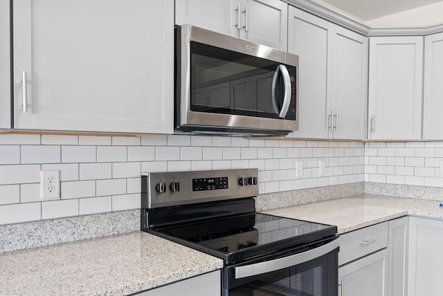 kitchen featuring appliances with stainless steel finishes, backsplash, light stone counters, and white cabinets