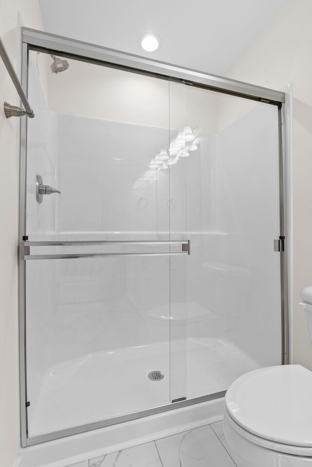 bathroom featuring an enclosed shower, toilet, and tile patterned flooring