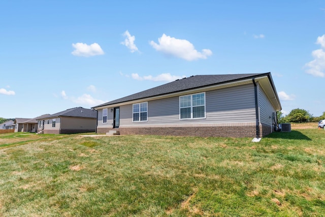 rear view of house with central AC and a yard