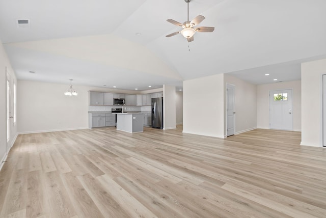 unfurnished living room featuring light hardwood / wood-style flooring, high vaulted ceiling, and ceiling fan with notable chandelier