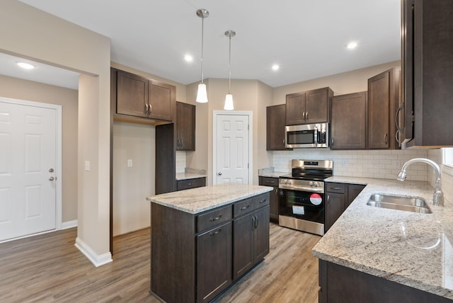 kitchen with hanging light fixtures, a center island, tasteful backsplash, appliances with stainless steel finishes, and sink