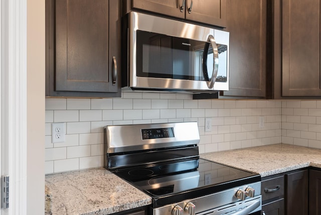 kitchen with stainless steel appliances, light stone counters, tasteful backsplash, and dark brown cabinetry