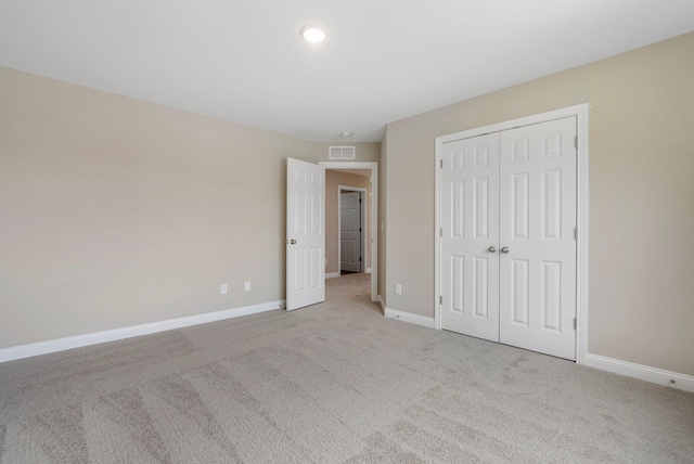 unfurnished bedroom with light colored carpet and a closet