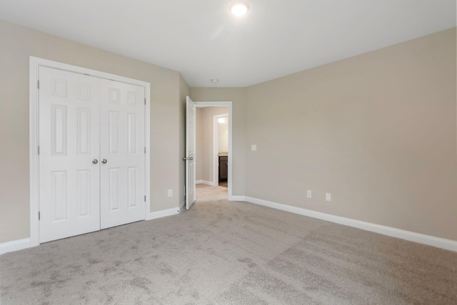 unfurnished bedroom with light colored carpet and a closet