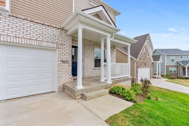 entrance to property featuring a yard, covered porch, and a garage