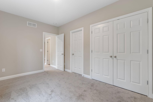 unfurnished bedroom with light colored carpet and a closet