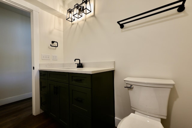 bathroom with baseboards, vanity, toilet, and wood finished floors