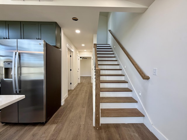 staircase with baseboards, wood finished floors, and recessed lighting