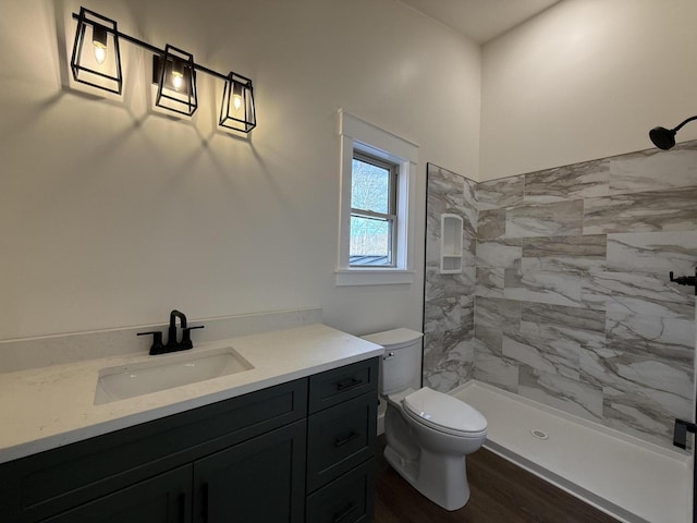 full bath featuring a stall shower, vanity, toilet, and wood finished floors