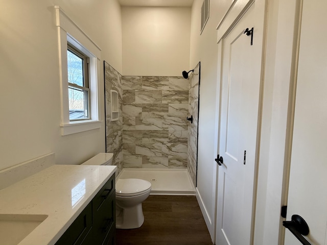 full bath with visible vents, toilet, vanity, a shower stall, and wood finished floors