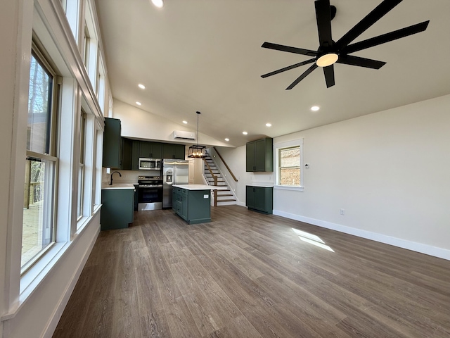 kitchen featuring stainless steel appliances, open floor plan, light countertops, a center island, and pendant lighting