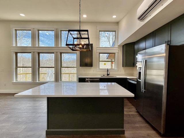 kitchen featuring pendant lighting, light stone counters, stainless steel refrigerator with ice dispenser, and a center island