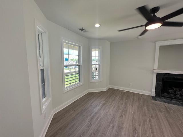 unfurnished living room featuring ceiling fan, a high end fireplace, and dark wood-type flooring