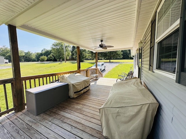 wooden terrace featuring grilling area, ceiling fan, and a lawn