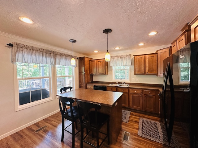 kitchen featuring a center island, black appliances, a kitchen breakfast bar, dark hardwood / wood-style floors, and decorative light fixtures