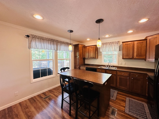 kitchen with a breakfast bar, dark wood-type flooring, sink, a kitchen island, and hanging light fixtures