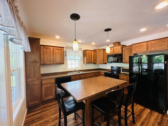 kitchen featuring a center island, black appliances, sink, dark hardwood / wood-style floors, and a kitchen bar