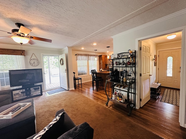 living room with a textured ceiling, dark carpet, ceiling fan, and crown molding