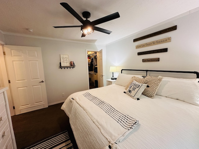 bedroom with a spacious closet, a closet, ceiling fan, and crown molding