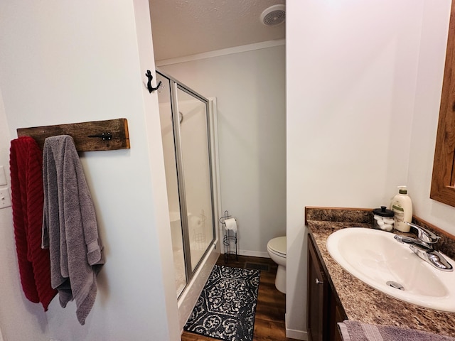 bathroom with wood-type flooring, vanity, toilet, and a shower with door