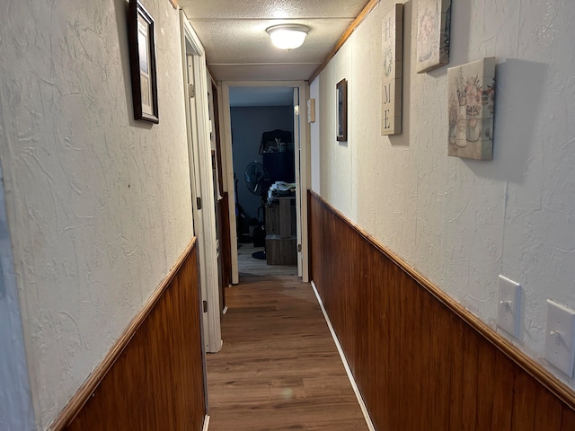 hallway with a textured ceiling and hardwood / wood-style floors