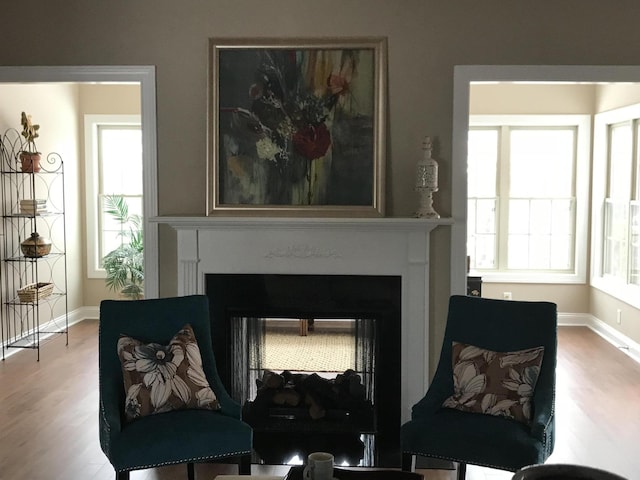 sitting room featuring a multi sided fireplace and hardwood / wood-style floors