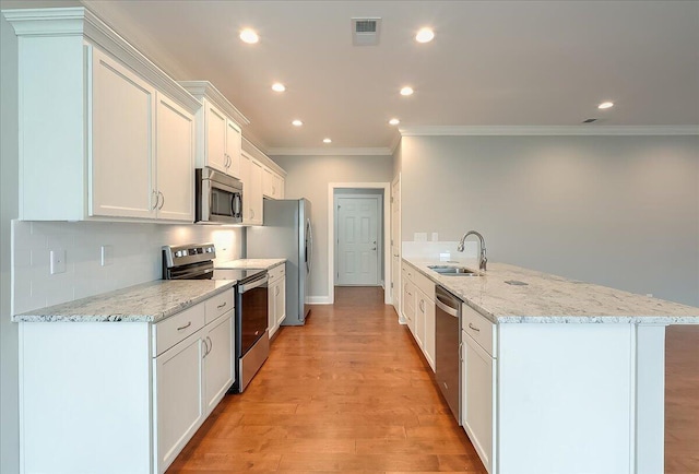 kitchen with light stone countertops, appliances with stainless steel finishes, ornamental molding, sink, and white cabinetry