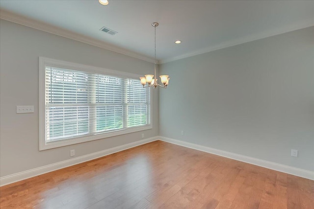 spare room with a chandelier, hardwood / wood-style floors, and ornamental molding